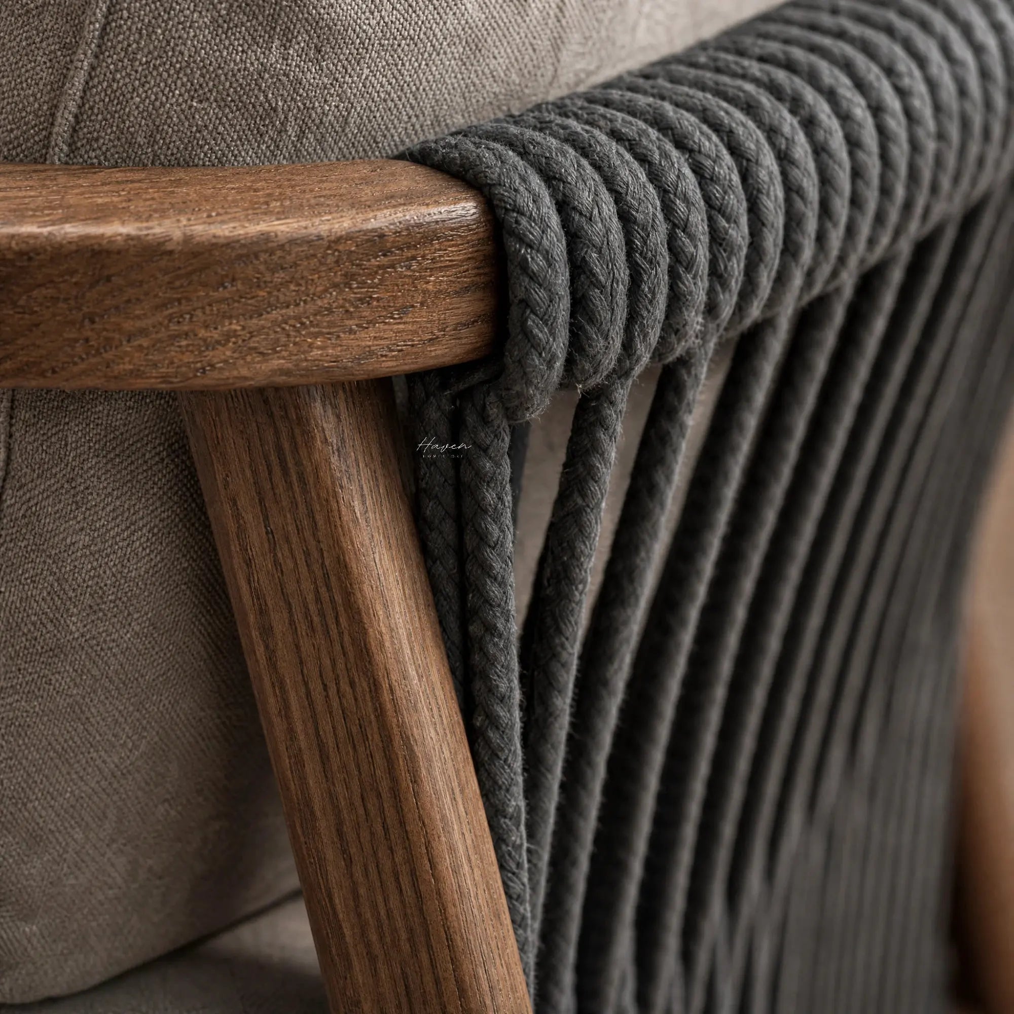 Dark rope detailing on the curved walnut wood armrest and grey upholstery of the Kiso lounge chair.