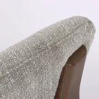 Close-up of textured pumice upholstery on a curved chair back, revealing the solid ash timber frame beneath the soft fabric.