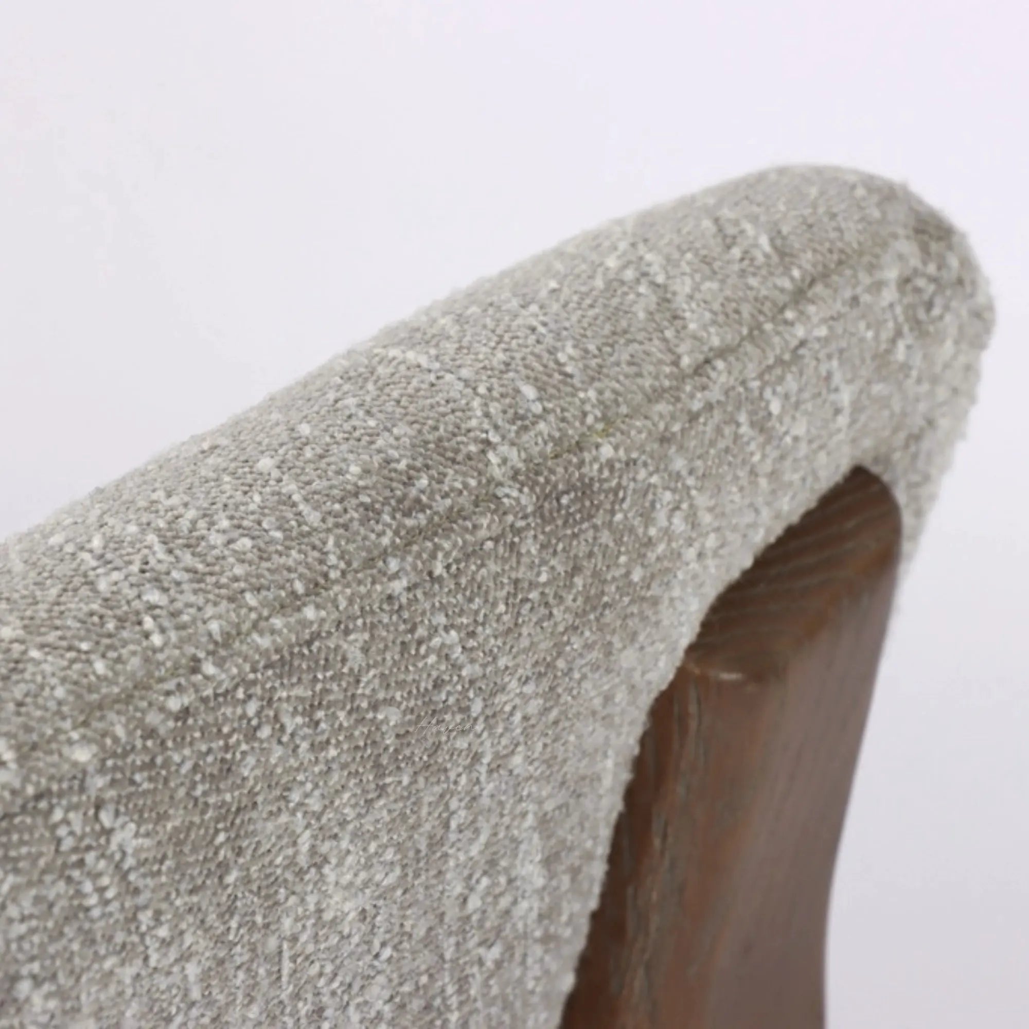 Close-up of textured pumice upholstery on a curved chair back, revealing the solid ash timber frame beneath the soft fabric.