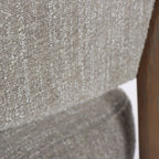 Textured pumice upholstery and curved ash timber frame of the Seki Chair, highlighting soft fabric against solid wood structure.