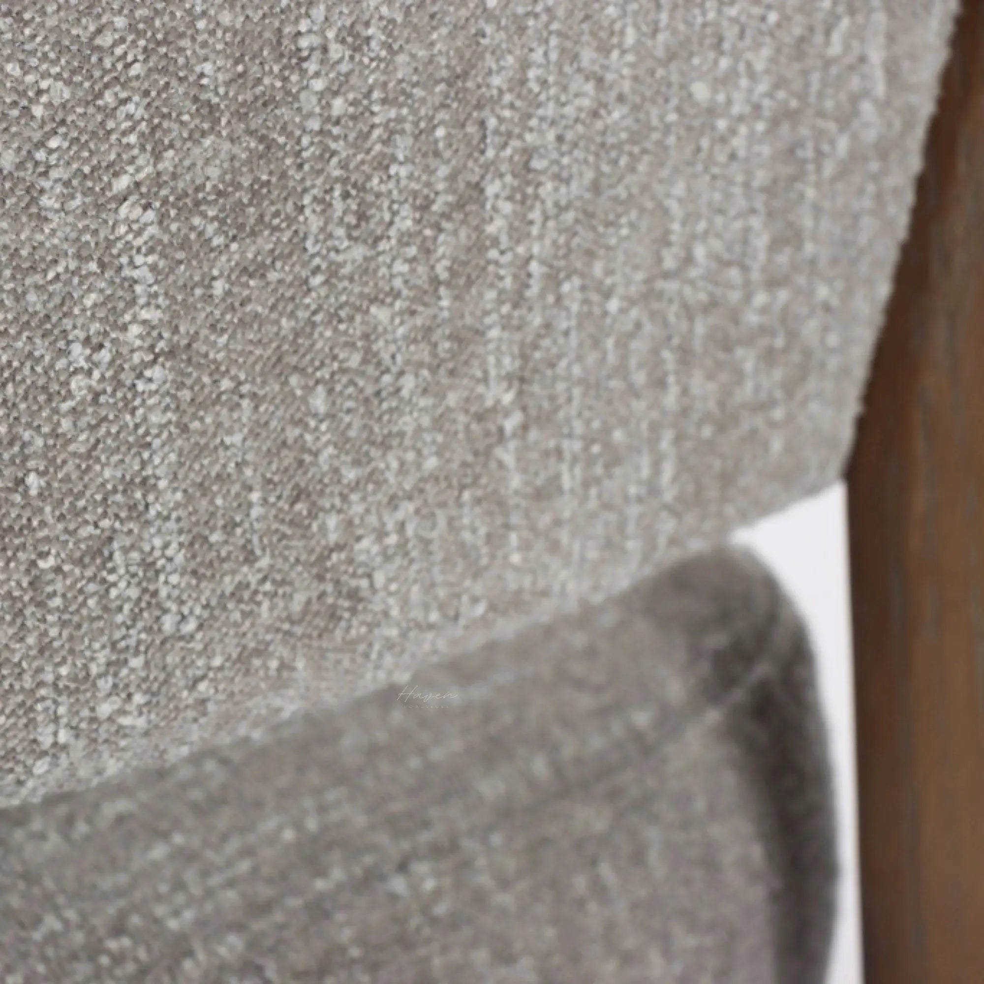 Textured pumice upholstery and curved ash timber frame of the Seki Chair, highlighting soft fabric against solid wood structure.