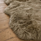 Taupe double sheepskin rug with long wool texture draped on wooden floor