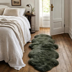 Thyme double sheepskin rug with long, soft wool laid on hardwood floor beside a linen-draped bed in a cozy bedroom.