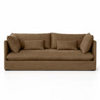Low-set mocha linen slipcover sofa featuring relaxed tailored fabric, loose back cushions, and rectangular throw pillows.