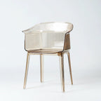 Sculptural translucent amber polycarbonate chair with wraparound silhouette and fine vertical textural detailing on back and seat.
