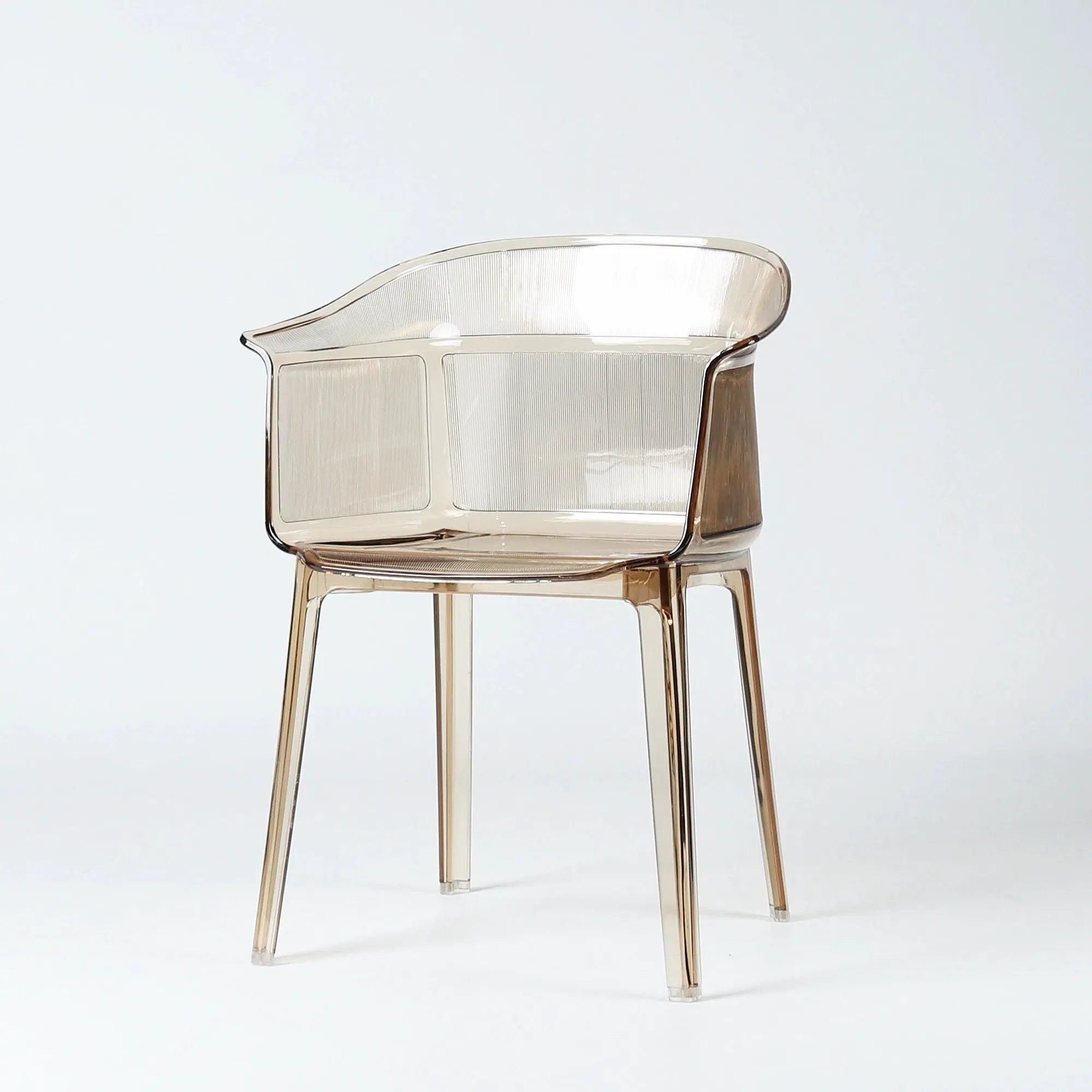 Sculptural translucent amber polycarbonate chair with wraparound silhouette and fine vertical textural detailing on back and seat.