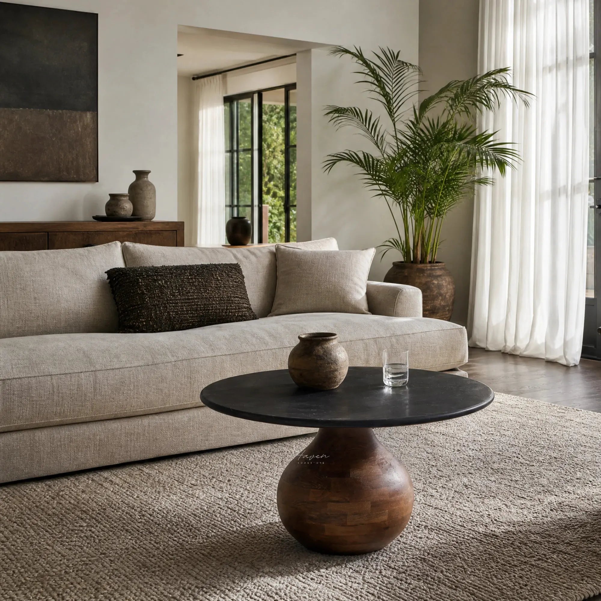 Round coffee table with black marble top and rounded mango wood pedestal base in a living room.