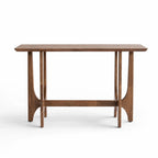 Slender rubber wood console table with softly sculpted supports and open framework, featuring a warm timber tone and light architectural presence.