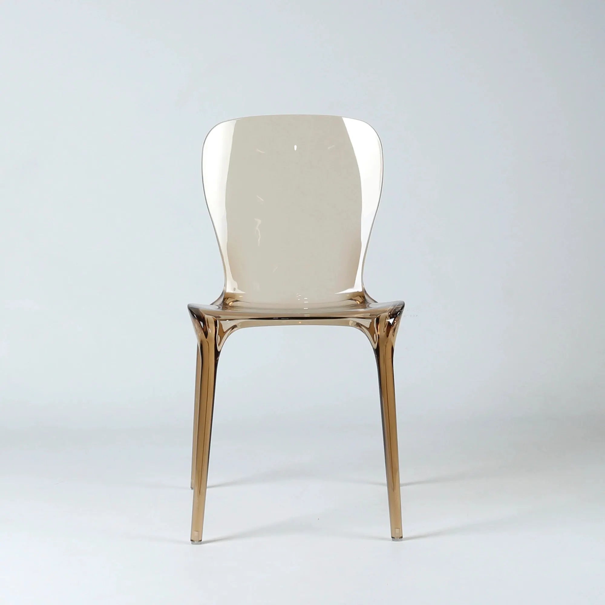 Transparent amber polycarbonate dining chair with curved back, continuous moulded construction, and slender legs.