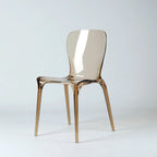 Amber transparent polycarbonate dining chair featuring a continuous moulded shell, softly curved back, and slender legs.