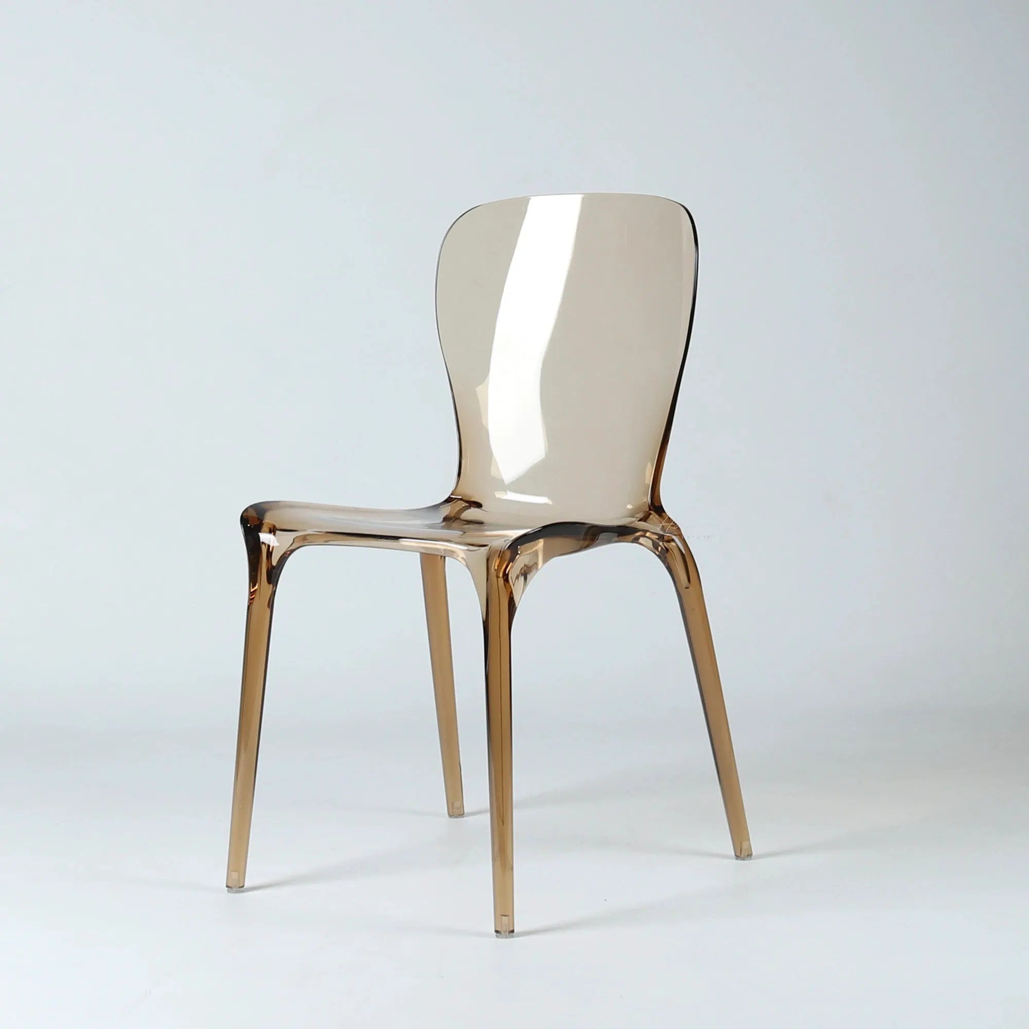 Amber transparent polycarbonate dining chair featuring a continuous moulded shell, softly curved back, and slender legs.