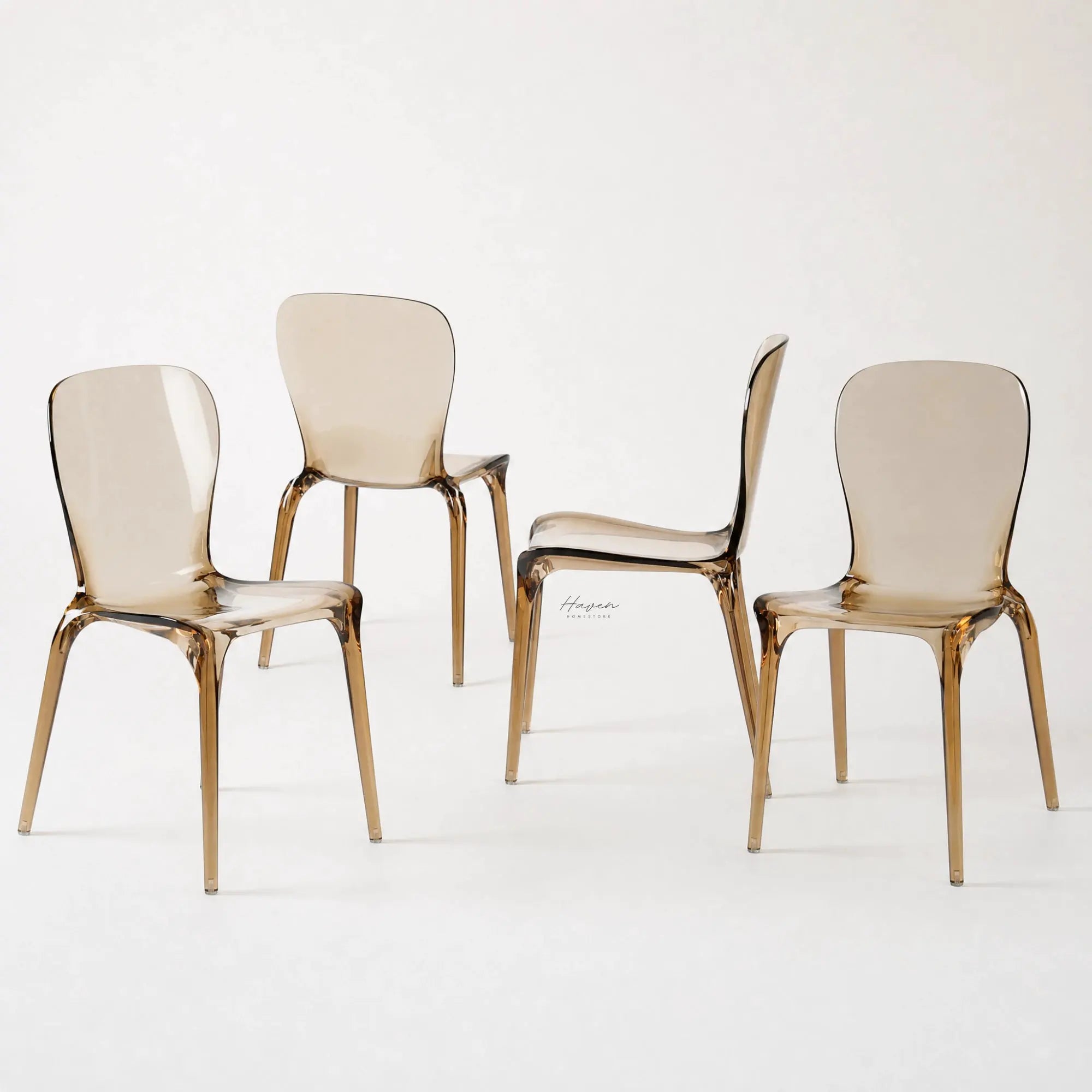 Set of four amber transparent polycarbonate dining chairs with curved backs and slender legs.