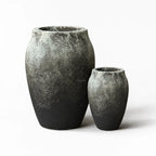 Textured black-grey fibre cement planters set with rounded volcanic forms and weathered finish.