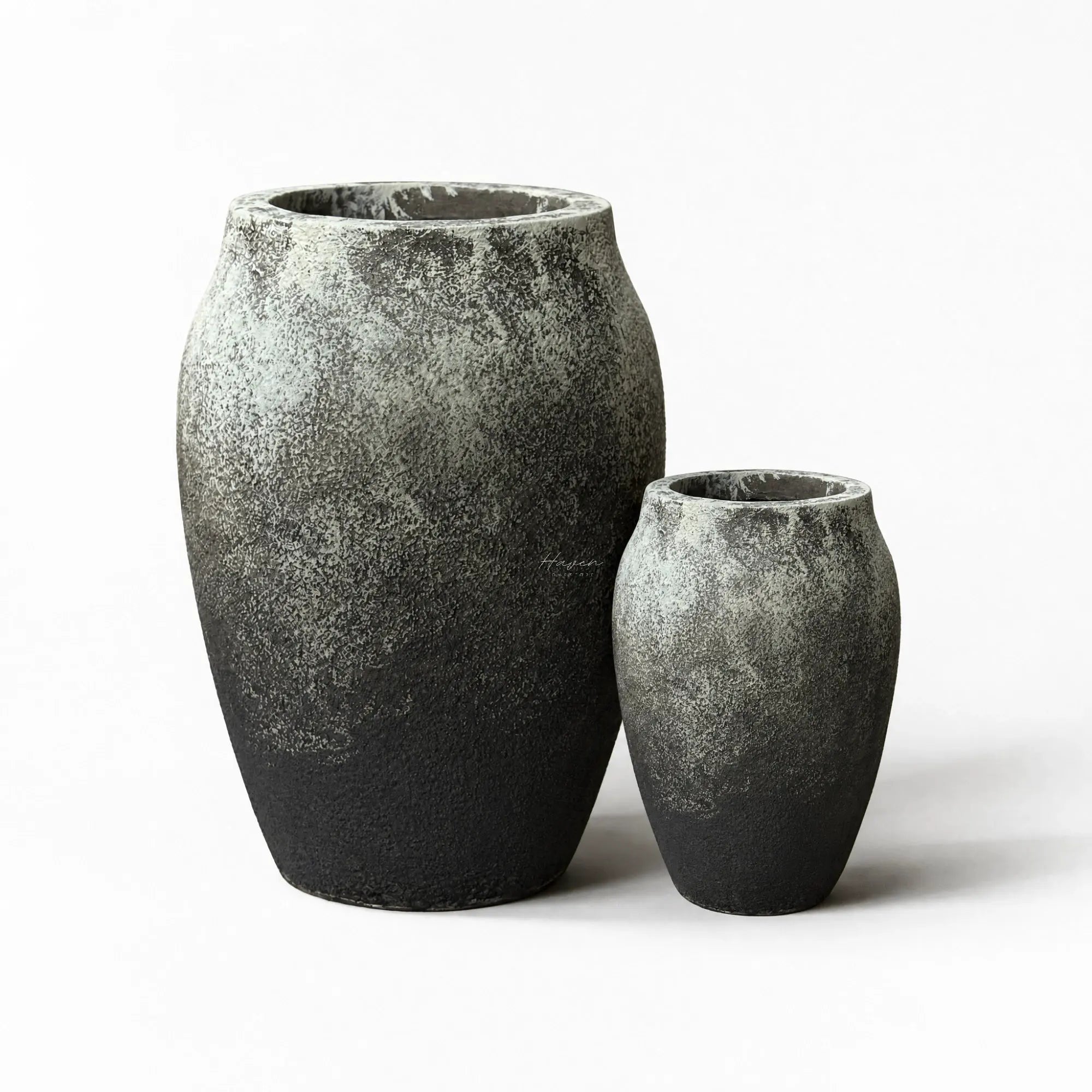 Textured black-grey fibre cement planters set with rounded volcanic forms and weathered finish.