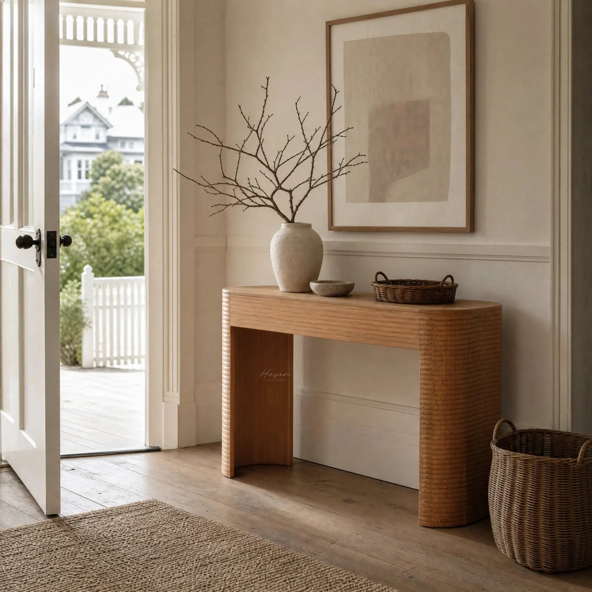 Elva Console in warm mindi timber with rounded silhouette, linear carved detailing, paired with vase and abstract art.