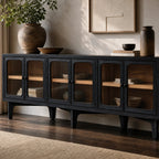 Long, low Kado Sideboard in dark timber with rounded glass doors revealing warm ash wood interior and shelved decor.