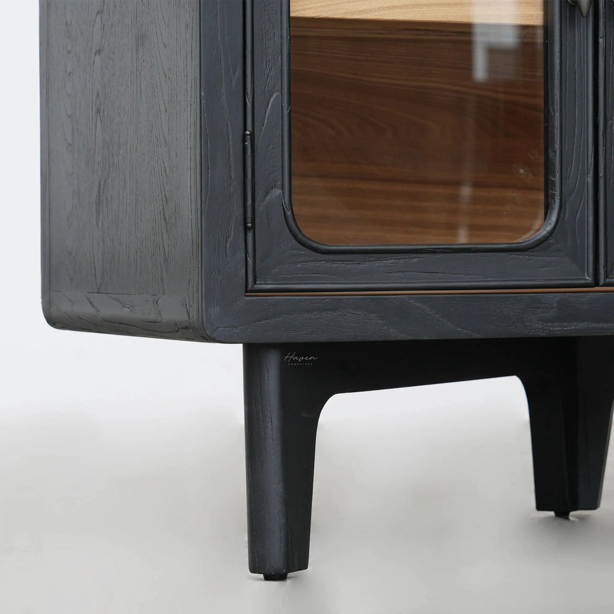 Kado sideboard details showing dark timber finish, rounded glass-fronted door corner, and tapered ash leg.