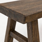 Reclaimed elm bench detail with broad seat, substantial legs, and visible grain texture showcasing honest architectural presence.