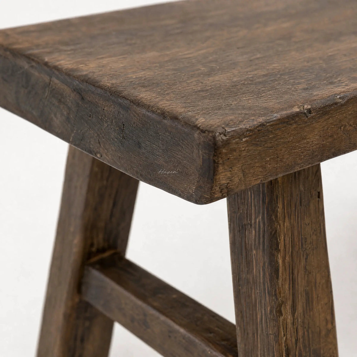 Reclaimed elm bench detail with broad seat, substantial legs, and visible grain texture showcasing honest architectural presence.