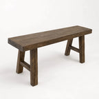 Reclaimed elm bench with broad seat, substantial legs, and irregular timber surface offering architectural presence.