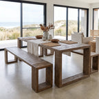 Reclaimed elm dining bench with substantial open box legs and irregular grain, paired with matching table in coastal dining space.