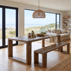 Reclaimed elm Estuary dining table and matching bench with block legs, set in a bright coastal living space featuring ocean views.