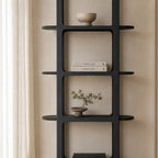 Tall black architectural shelf with rounded corners and side extensions, displaying books and ceramics against a beige wall.