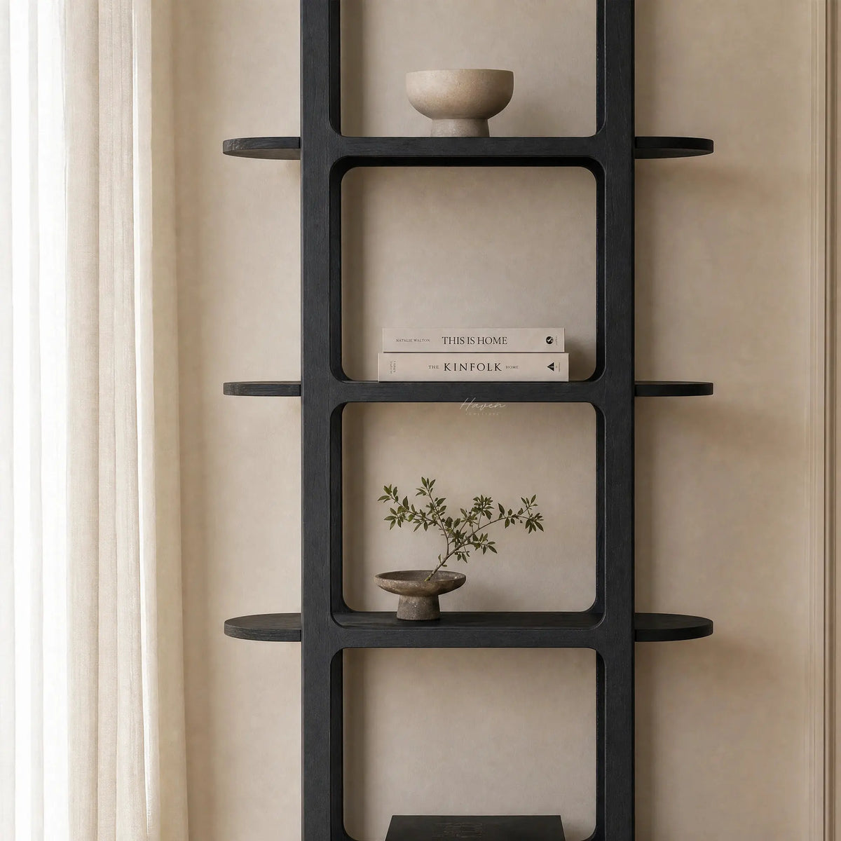 Tall black architectural shelf with rounded corners and side extensions, displaying books and ceramics against a beige wall.