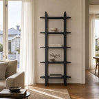 Tall black architectural bookcase with rounded corners and shelves extending beyond vertical supports, styled with books and decor in a bright living room.
