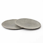 Set of two grey riverstone plates with a low, broad profile and softly uneven organic edges against a white background.
