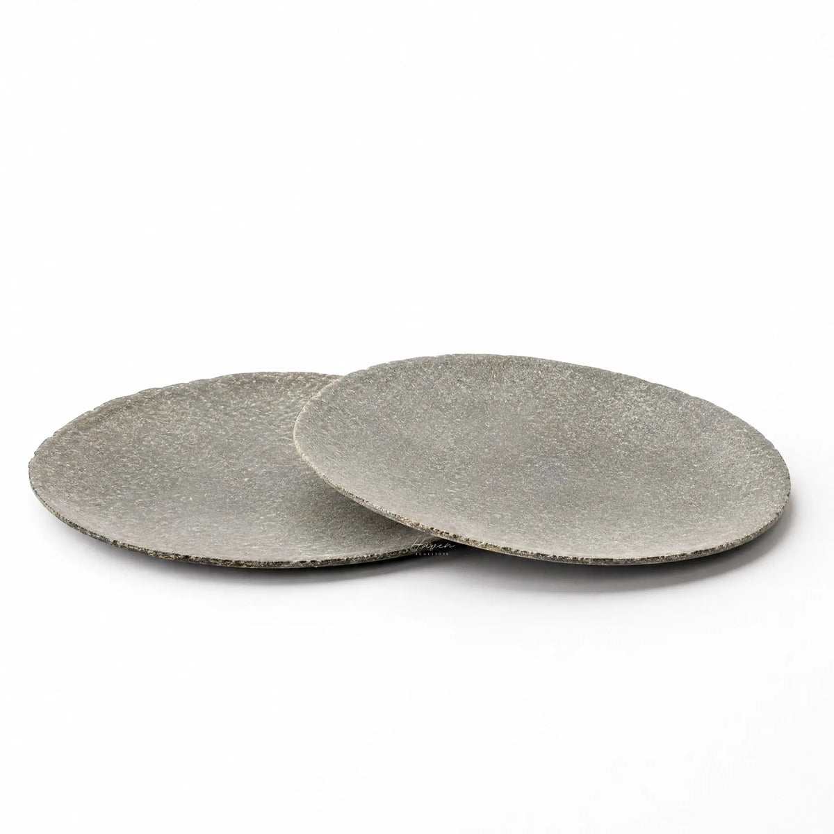 Set of two grey riverstone plates with a low, broad profile and softly uneven organic edges against a white background.