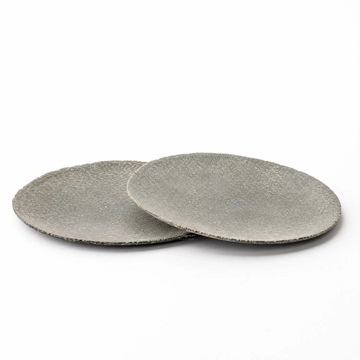 Set of two grey riverstone plates with a low, broad profile and softly uneven organic edges against a white background.