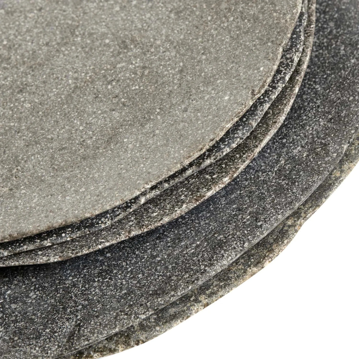 Stacked riverstone ceramic plates featuring a speckled grey texture, softly uneven edges, and a sculptural, elemental aesthetic.