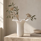 White bone china Mushroom Vase XL features a sculptural floral silhouette with a undulating rim and subtle vertical texture holding dried branches.