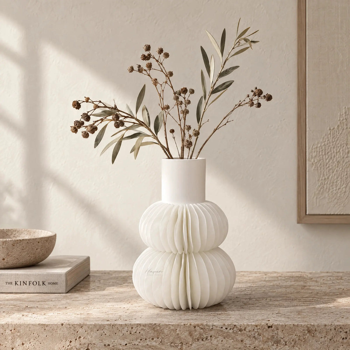 White bone china pleated frill vase with tiered sculptural form holding dried branches on a stone surface.