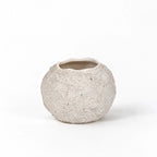 Rounded, low-set terracotta vase with a chalky off-white finish, textured grain, and irregular rim.