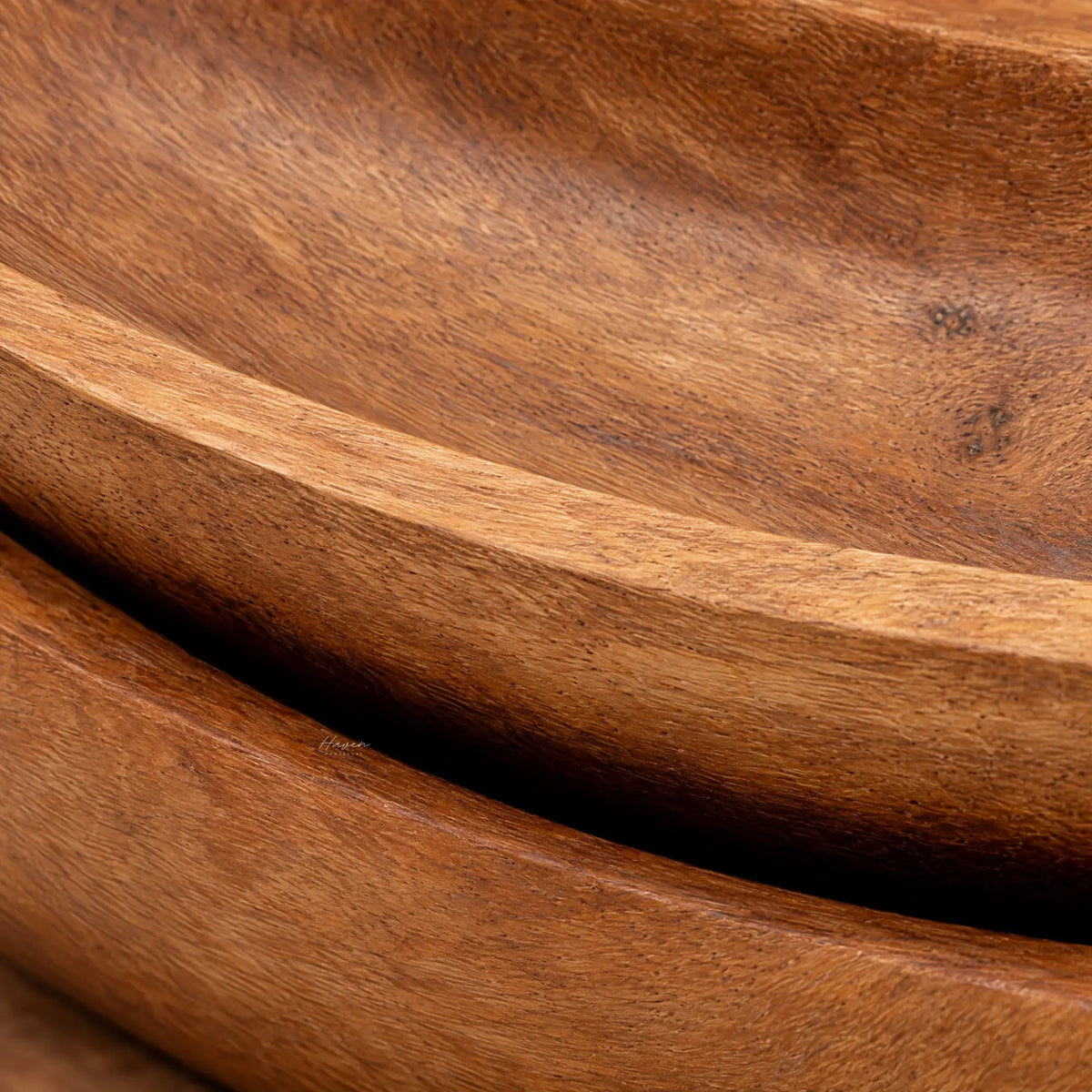 Close-up of solid teak oval trays featuring gently upturned edges, warm brown tones, and visible natural wood grain texture.