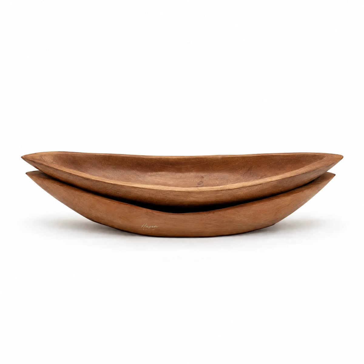 Stacked oval teak trays with warm brown tones, visible grain, and gently upturned edges carved from solid wood.