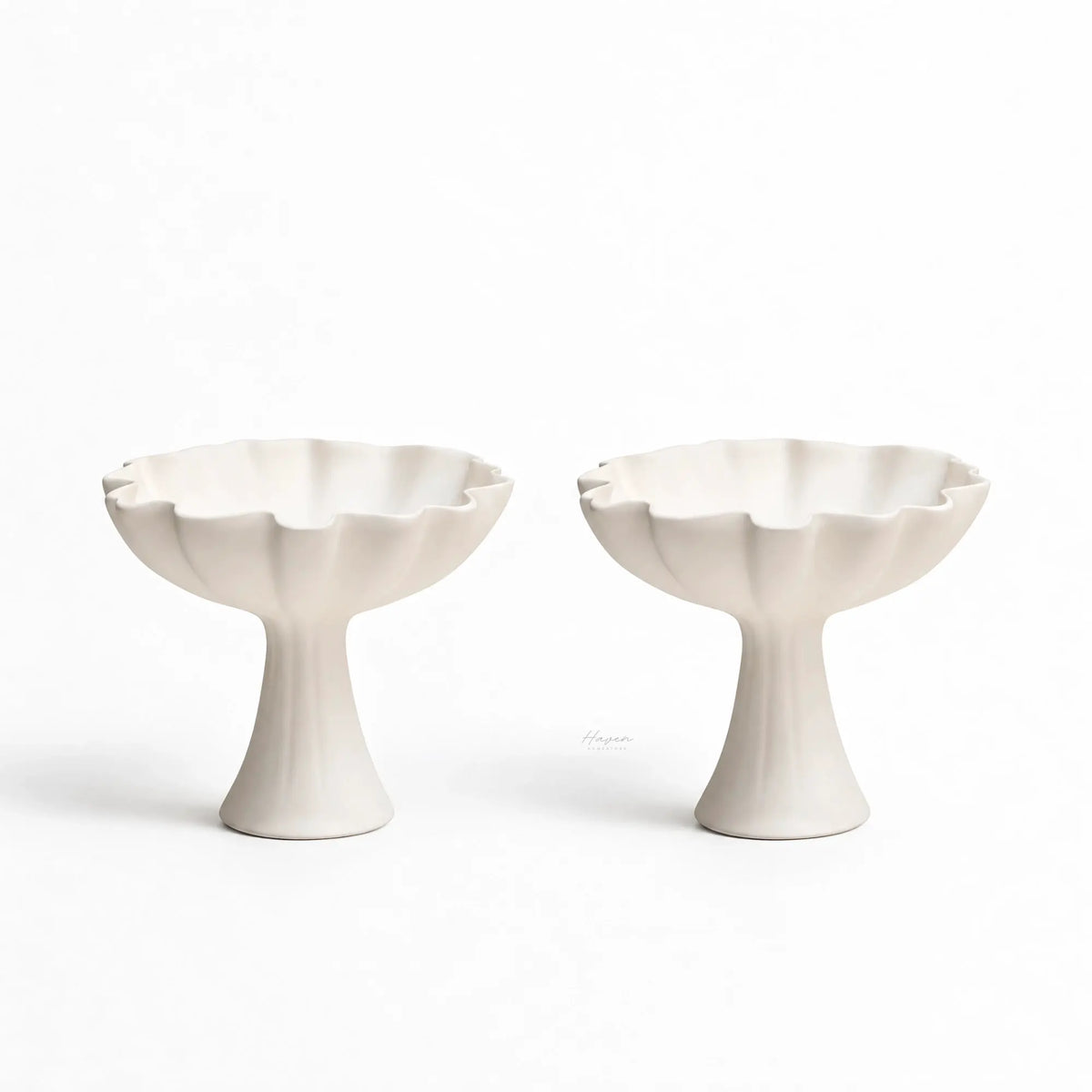 Pair of white bone china ruffle pedestal dishes featuring fluted bowls, slender bases, and gently undulating rims.