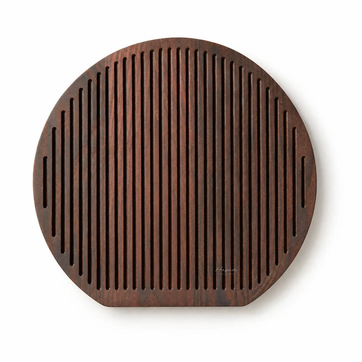 Round Yami cheese board with deep carbonised ash finish and rhythmic linear grooves for a sculptural serving presentation.