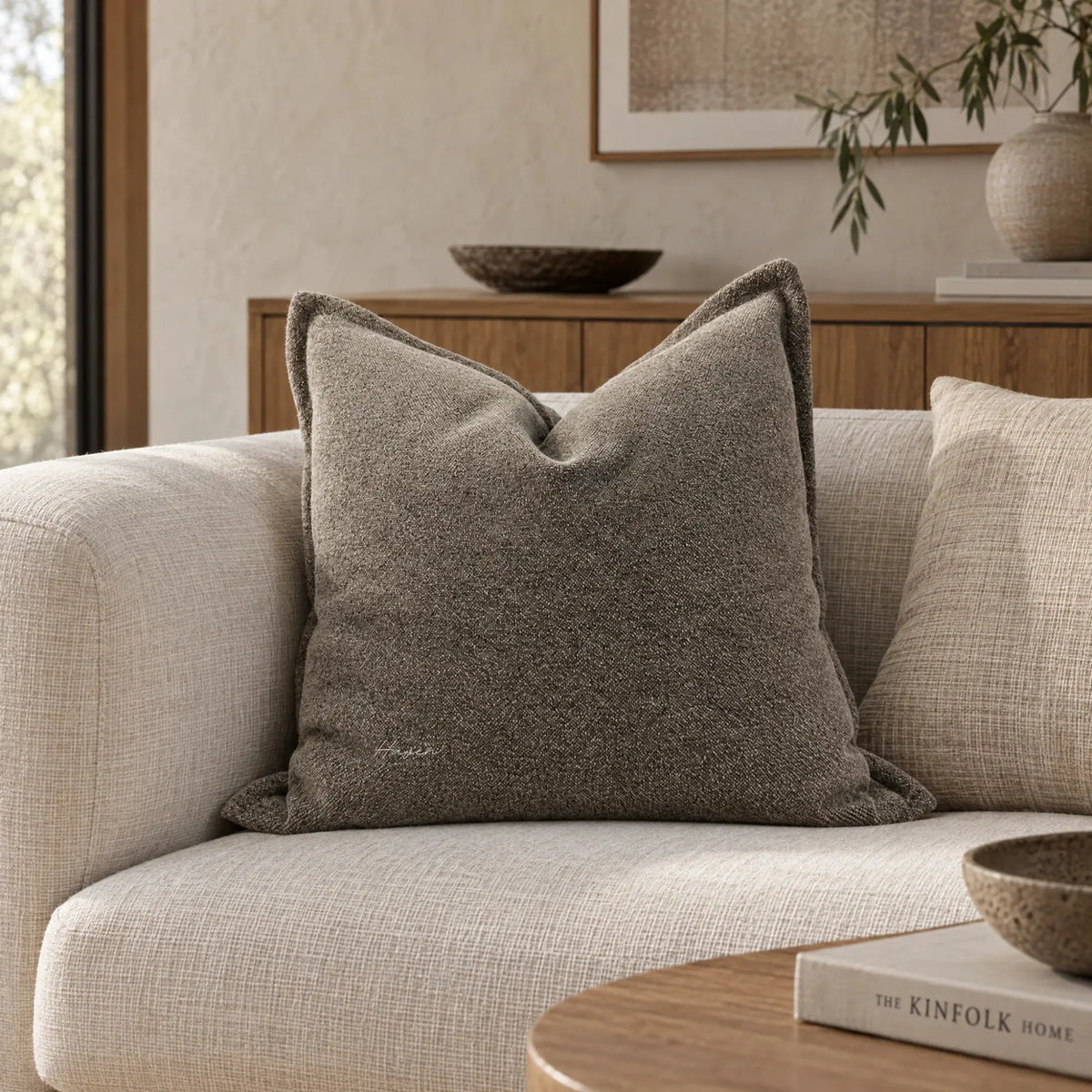 Textured Fawn cushion cover with woven surface and tonal variation resting on a light sofa in a warm living space.