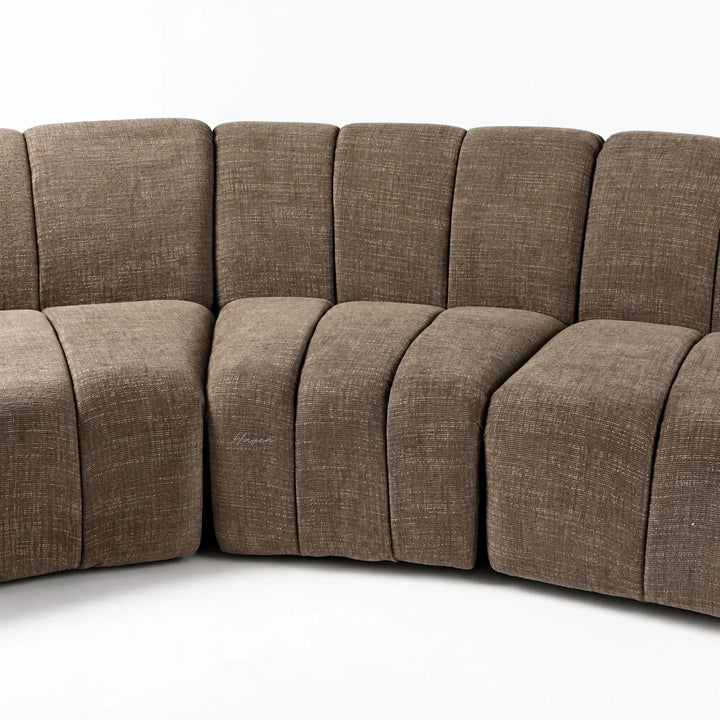 Curved Ethernet Modular Sofa in Truffle featuring softly segmented backrests and textured polyester upholstery with a low 70cm profile.