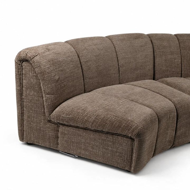 Softly segmented truffle modular sofa with a low profile, featuring textured polyester upholstery and a relaxed architectural design.