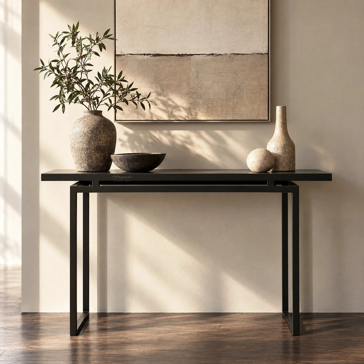 Slim metal console table in greyed-brown with an architectural frame, styled with ceramic vases and greenery against a neutral wall.