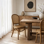 Margaux Dining Chair with oak frame and woven natural rattan seat and back, set around a rustic wooden table