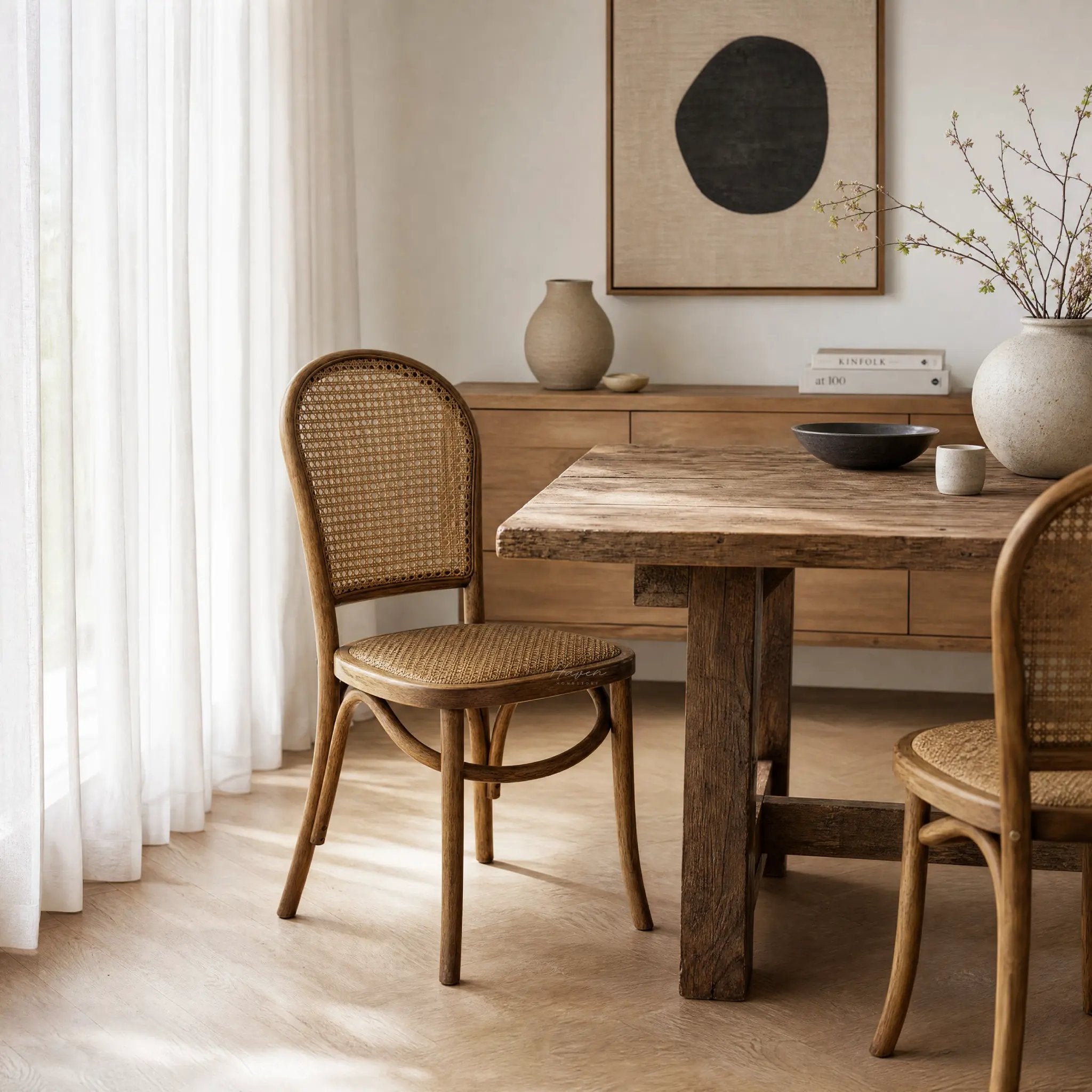 Margaux Dining Chair with oak frame and woven natural rattan seat and back, set around a rustic wooden table