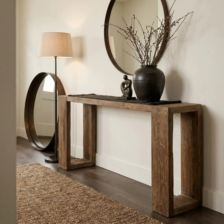 Casa Console in reclaimed elm with aged black wash, paired with a round mirror and twig vase in an entryway.