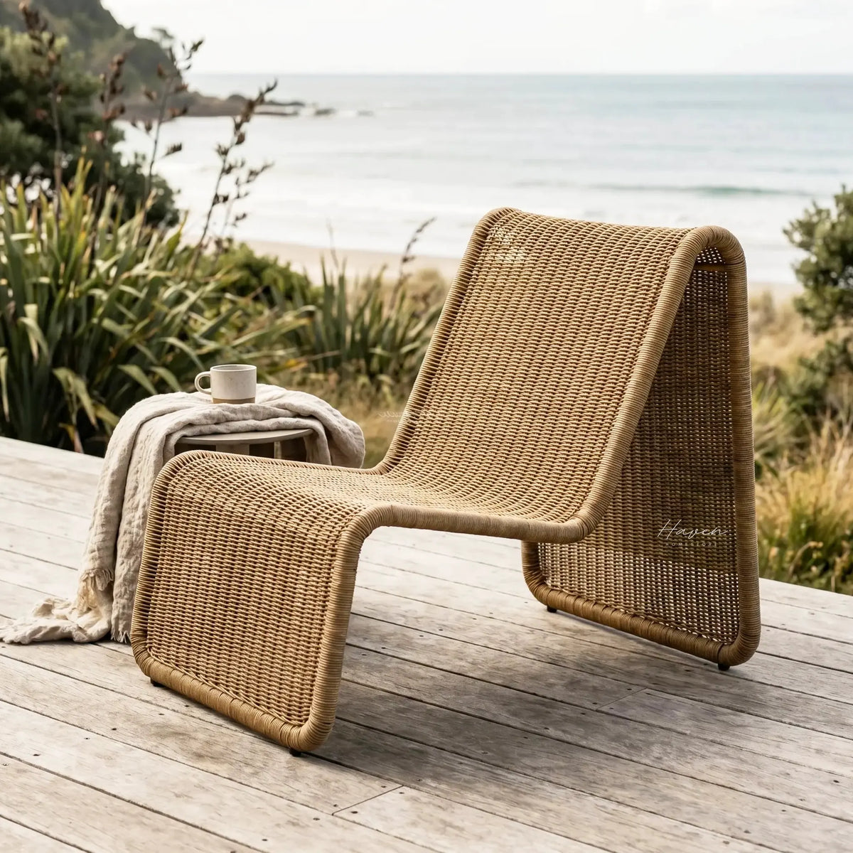 Marina outdoor lounge chair on a wooden coastal deck with woven rattan and ocean view.