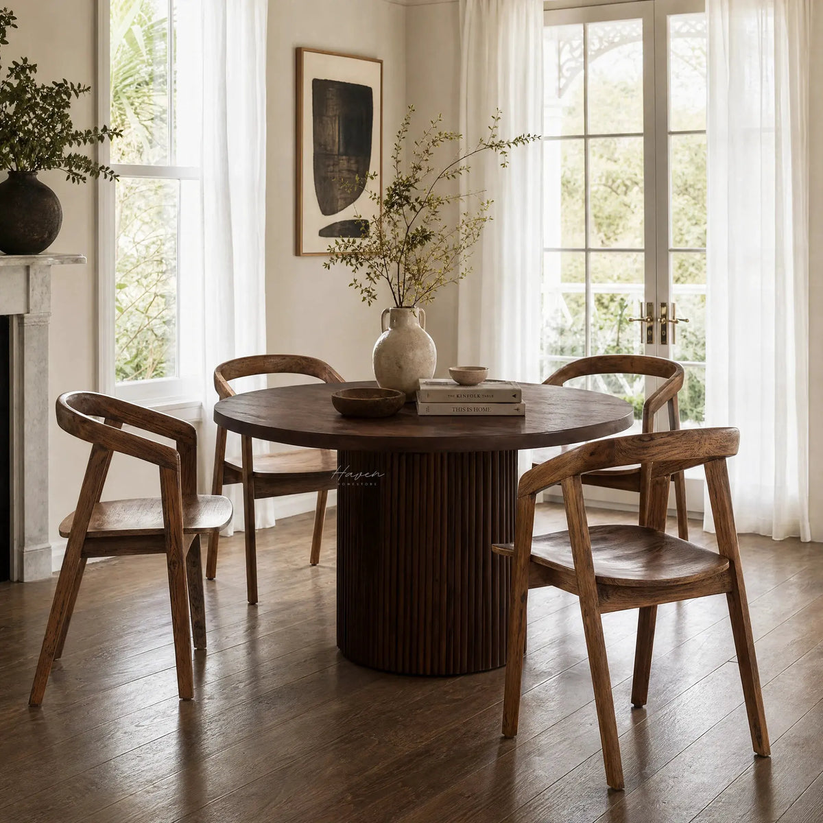 Dune Teak Dining Chair around a round teak table in a sunlit dining room with white curtains.
