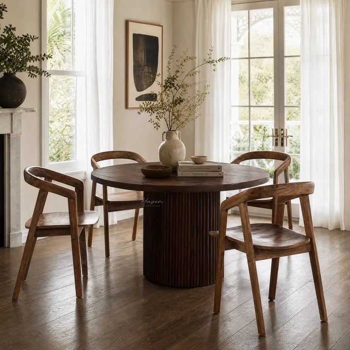 Dune Teak Dining Chair around a round teak table in a sunlit dining room with white curtains.